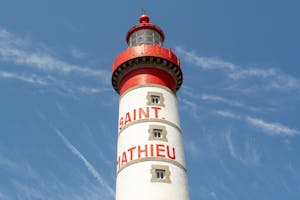 Close-up of Saint Mathieu lighthouse with striking red and white design against a clear blue sky.